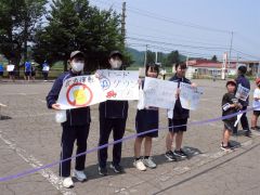 手書きのボードと小旗を手にする小中学生