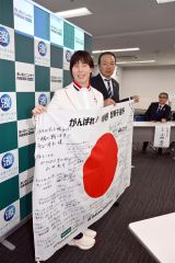 あいおいニッセイ同和損害保険の加川克仁地域担当常務出稿役員（後方）から寄せ書きの「日の丸」を受け取り、笑顔を見せる小野選手（手前）＝金野和彦撮影