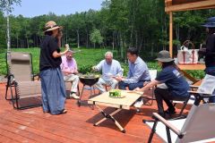 テラスでバーベキューを実演する砂金社長（左から３人目）と与田氏（同４人目）