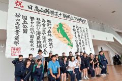 会場入り口に飾られた書道パフォーマンスの作品を前に記念撮影する書道部の生徒たち