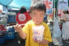 「猛暑日」となった帯広で、汗をかきながらかき氷を食べて「冷たい」と笑う子ども（２１日午後１時２５分ごろ、帯広市街地で開催された帯広市まちなか歩行者天国で）