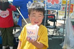 「猛暑日」となった帯広で汗をかきながらありついたかき氷に笑顔を見せる子ども（２１日午後１時２０分ごろ、帯広市街地で開催された帯広市まちなか歩行者天国で）