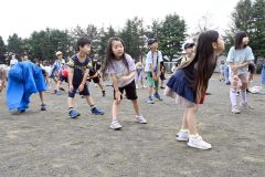 小雨が降る中ラジオ体操を行う子どもたち（２４日午前７時ごろ）