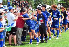 湖畔に５点目を上げ、チーム勝利に貢献したスカイアースのＭＦ佐藤瑠己安（青色ユニホーム、左手前、池田町地域おこし協力隊）。試合後、プライベートで応援に駆けつけた安井美裕池田町長がたたえる場面も（金野和彦撮影）