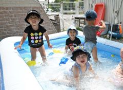 ２歳児クラスでは日よけの下にプールを設置。自然と笑顔がこぼれる子どもたち。