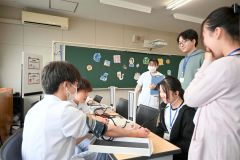 聴診器を付け、血液が流れる音を聞く高校生