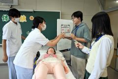 聴診器を付け、人形から聞こえる心臓の異常音を聞き分ける体験をする高校生