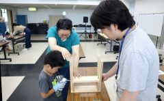 馬場さん(右)を講師に、電動ドリルを使って椅子作りに挑戦する親子ら