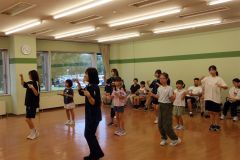 佐々木部長（前列右）と香川副部長（同左）の動きに合わせて踊る児童ら