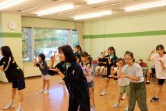 佐々木部長（前列右）と香川副部長（同左）の動きに合わせて踊る児童ら