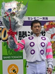 花束を掲げ、ファンの声援に応える鈴木騎手
