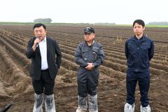 じゃがいも畑の前であいさつをする(左から)田崎一也社長、橋詰仁組合長、杉浦大斗幕別支所長(5日、午前10時ごろ、帯広市以平町で。金野和彦撮影)
