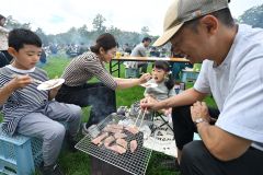 十勝和牛を炭火で焼いて味わう家族連れ(15日午前10時40分ごろ、須貝拓也撮影)