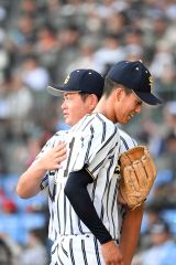【夏の甲子園大会1回戦・白樺学園-創成館】1回のピンチを切り抜けてベンチに引き上がる半澤理玖投手(手前)を亀田直紀監督が肩をたたいてねぎらう(8月11日、須貝拓也撮影)