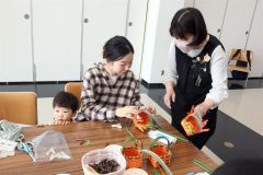 講師の飯島さん(右)のアドバイスで籠作りに挑戦する母親ら