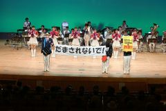 パフォーマンスの合間に寸劇で詐欺への注意を呼び掛ける音楽隊員ら