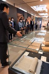 大和田さん(左)の解説を聞きながら展示資料を見る内覧会参加者