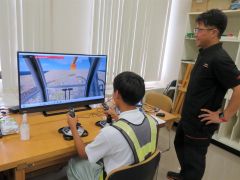 バックホウの操作をシミュレーターで体験する生徒