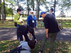 行方不明の認知症役の男性の靴に付いているQRコードを確認する参加者