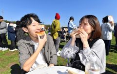 買い求めたあんパンを頬張る来場客(12日午11時40分、道の駅おとふけで。塩原真撮影)