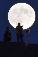 彗星観察に訪れた市民とスーパームーン(17日午後5時ごろ、帯広の森の「もりの山」で。塩原真撮影)