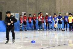 滑り方の基礎を教える清水宏保さん（手前）と熱心に話を聞く参加者